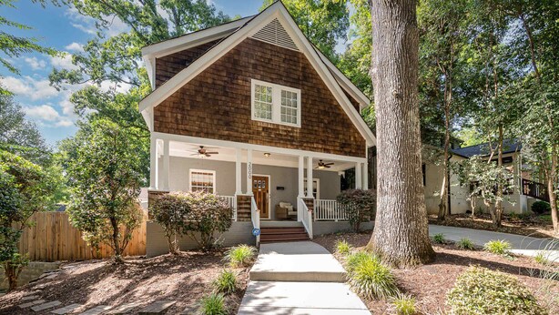 A two-story house with a front porch, a wooden exterior, and a driveway leading to the entrance. - Luxury South End Retreat - Hot Tub - 4 Bedrooms (Charlotte)