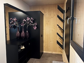 Eine moderne Küche mit einem schwarzen Schrank, zwei violetten Vasen mit Blumen und einer Holzwand.