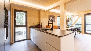 Eine moderne Küche mit Holzschränken, einer großen Kochinsel und einem Essbereich mit Stühlen und Tisch.