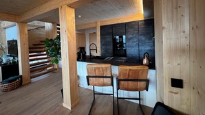 Eine moderne Küche mit Holzbalken, einer schwarzen Arbeitsplatte und zwei Barhocker.