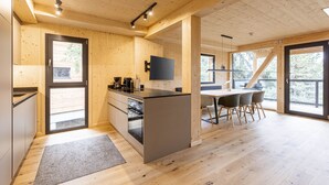 Una cocina moderna con una isla central, suelo de madera y una zona de comedor con mesa y sillas.