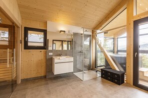 A modern bathroom with a glass shower, wooden walls, and a large window. - Superior Chalet # 16 with Sauna & Hot Tub (Turrach)