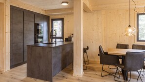 Eine moderne Küche mit Kochinsel, Holzwänden und einem Essbereich mit Tisch und Stühlen.