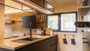 A modern kitchen with wooden walls, a large window, and a built-in sink.