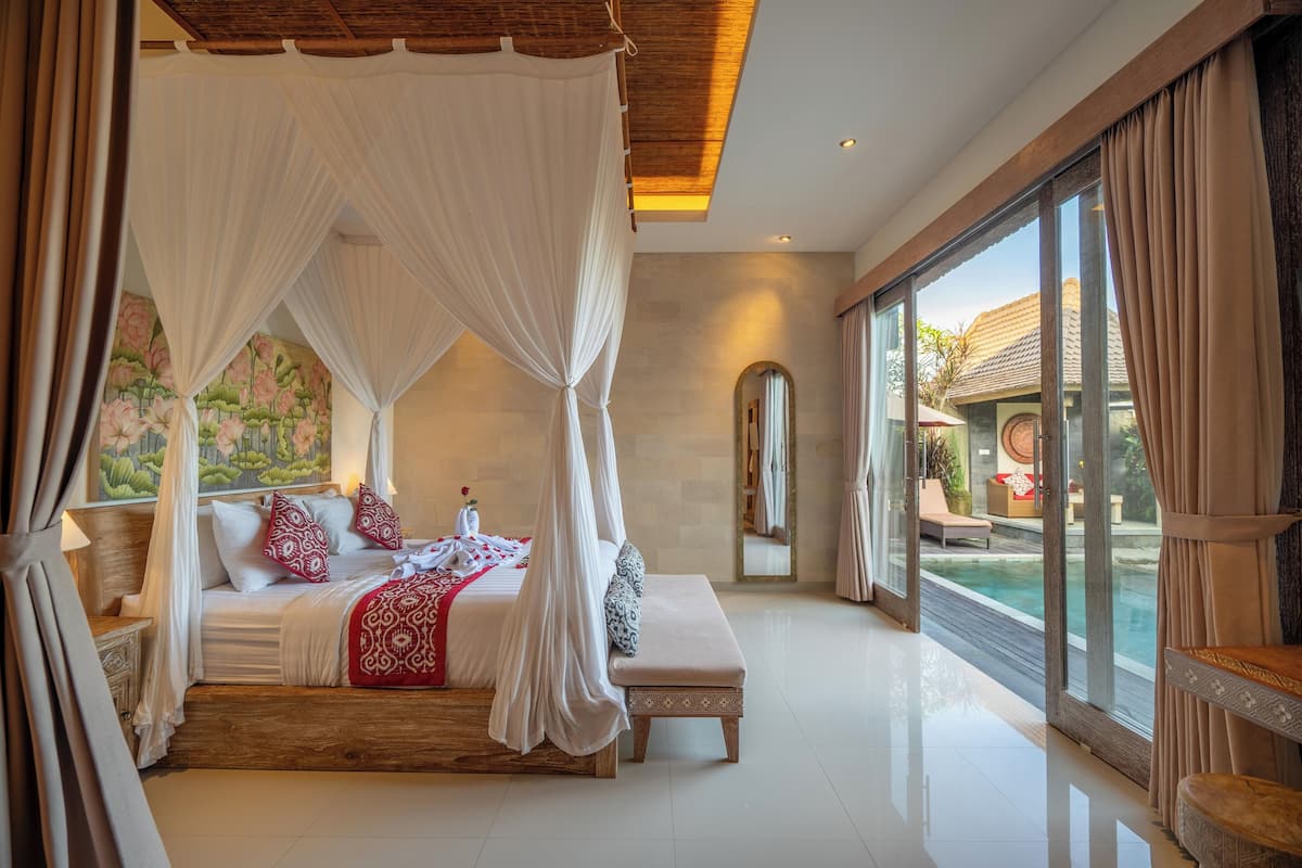 Ein geräumiges Schlafzimmer mit einem großen Bett, einer Bank und Blick auf einen Pool.