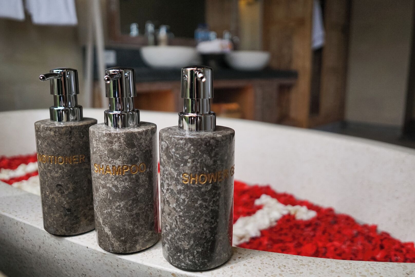 Three cylindrical bottles with pump dispensers labeled "Conditioner," "Shampoo," and "Shower Gel" on a countertop.