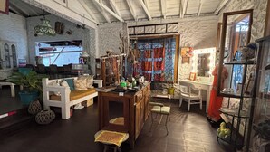 A cozy, rustic interior with a wooden bench, a small table, and a chair. There is a shelf with decorative items and a mirror with lights. - Posada 1914 (Panama City)
