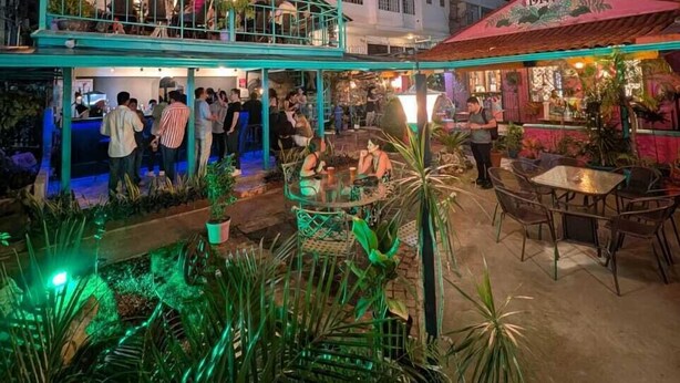 An outdoor bar area with seating and a pool, surrounded by tall buildings. - Posada 1914 (Panama City)