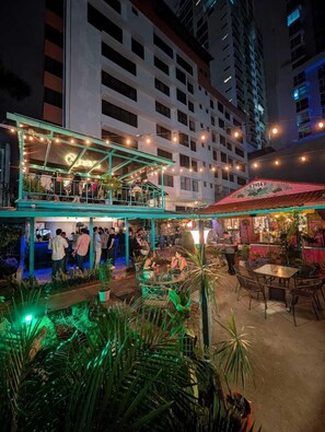 An outdoor bar area with seating and a pool, surrounded by tall buildings. - Posada 1914 (Panama City)