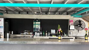 A bar area with a countertop, bar stools, a mirror, and various bottles. - Posada 1914 (Panama City)