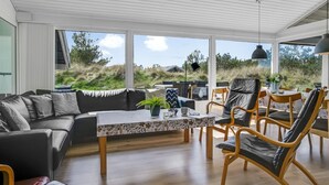 A modern living room with a sofa, chairs, a table, and large windows offering a view of the outdoors. - "Annlisa" - 1km from the sea by Interhome (Blokhus)