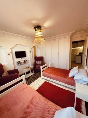 Un dormitorio con dos camas, televisión, una silla y una mesita.