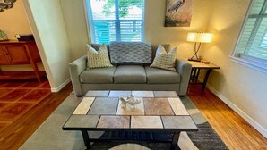 A living room with a sofa, a coffee table, a lamp, and a painting on the wall.
