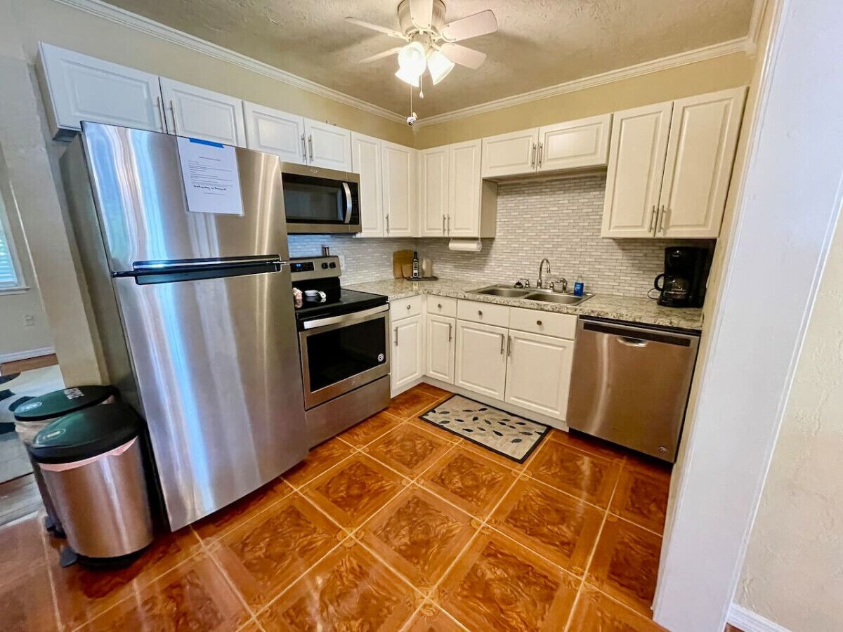 A kitchen with white cabinets, stainless steel appliances, and a tiled floor.