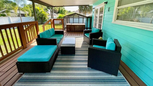 An outdoor deck with wicker furniture and a striped rug.