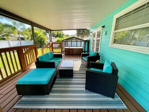 An outdoor deck with wicker furniture and a striped rug.