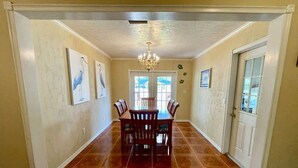 A dining area with a wooden table and chairs, a chandelier, and a door with a window.