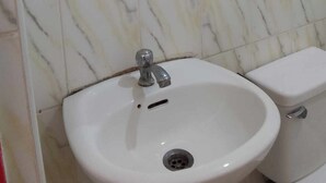 A bathroom with a marble-tiled wall, a white sink with a single faucet, and a toilet. - Wjv Inn Pusok (Lapu-Lapu)