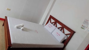 A single bed with a wooden headboard, white bedding, and two pillows with 'WJ Inn FUSOK' branding. - Wjv Inn Pusok (Lapu-Lapu)