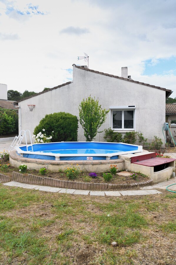 Relax by the pool surrounded by lush gardens and a charming home in the background.