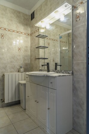 Bathroom features a large mirror above a sink and vanity, surrounded by beige tile walls with a decorative border.