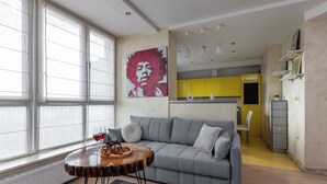 Uma sala de estar moderna com um sofá cinzento, uma mesa de centro de madeira e uma janela grande.