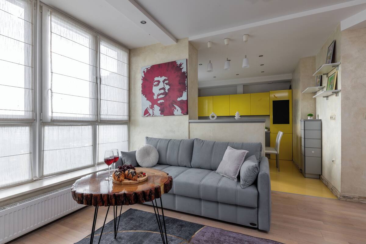 A modern living room with a grey sofa, a wooden coffee table, and a large window.