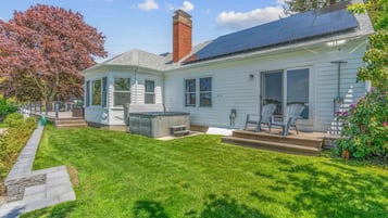 A house with a solar panel roof, a covered patio, and a well-maintained lawn.