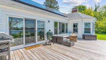 A deck with a grill, outdoor seating, and a view of a lake.