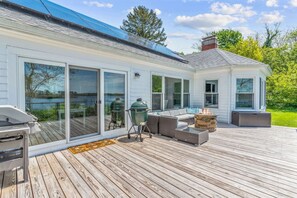Una terraza con una parrilla, asientos al aire libre y vista a un lago.
