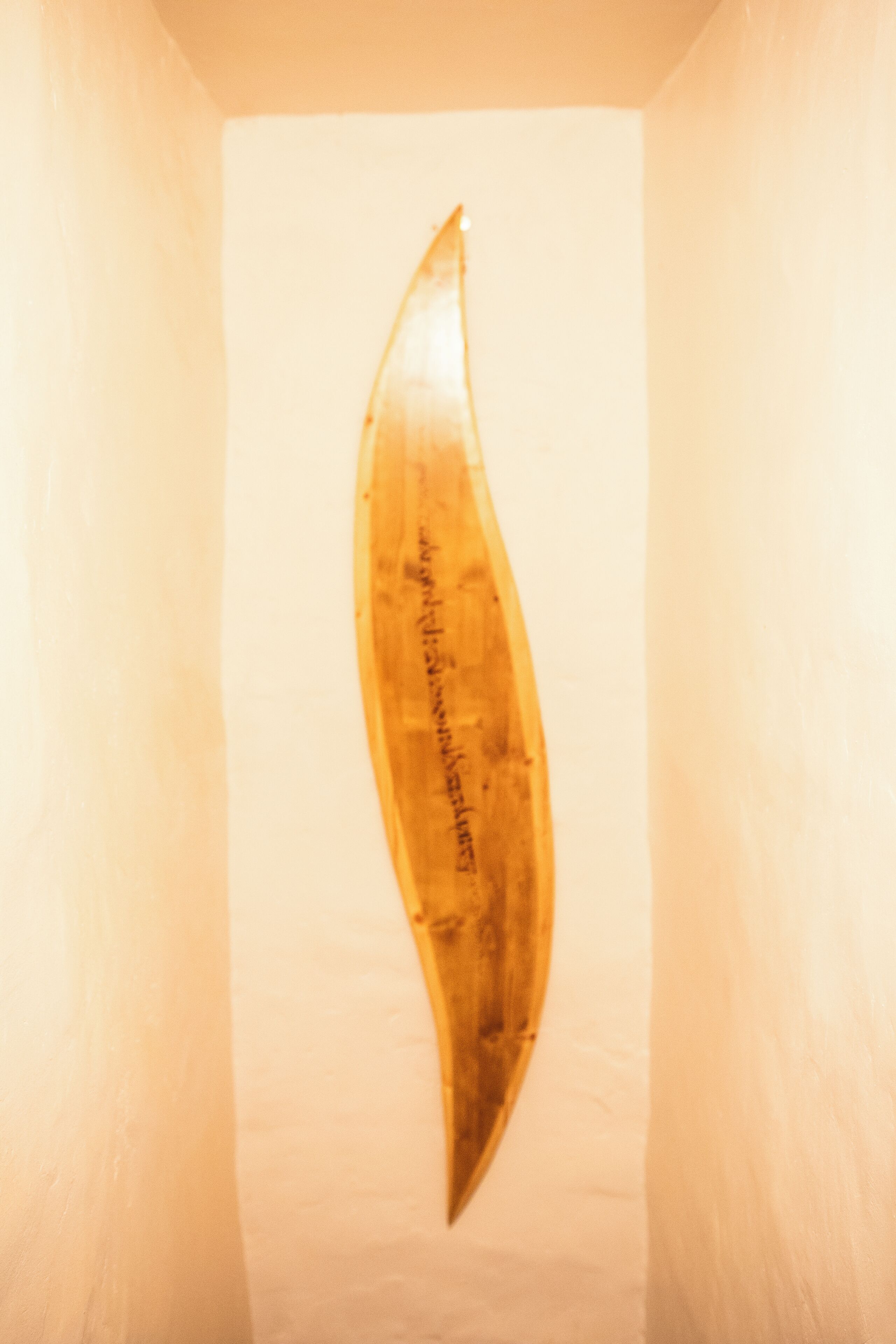 Un objet en bois portant une inscription, fixé au mur.