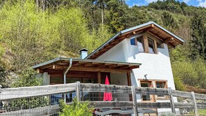Un moderno chalet di montagna con tetto spiovente, travi in legno e facciata bianca.