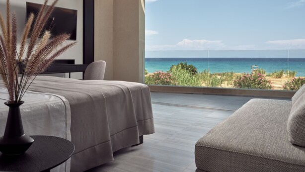 Una habitación moderna con una cama, una silla y vista al océano.