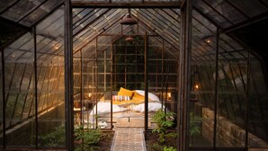 A greenhouse with a bed, plants, and a brick pathway. - La Petite For t Antique Countryside Greenhouse (Asse)
