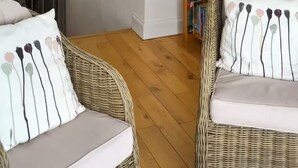 A room with wicker furniture and white cushions with a floral pattern.