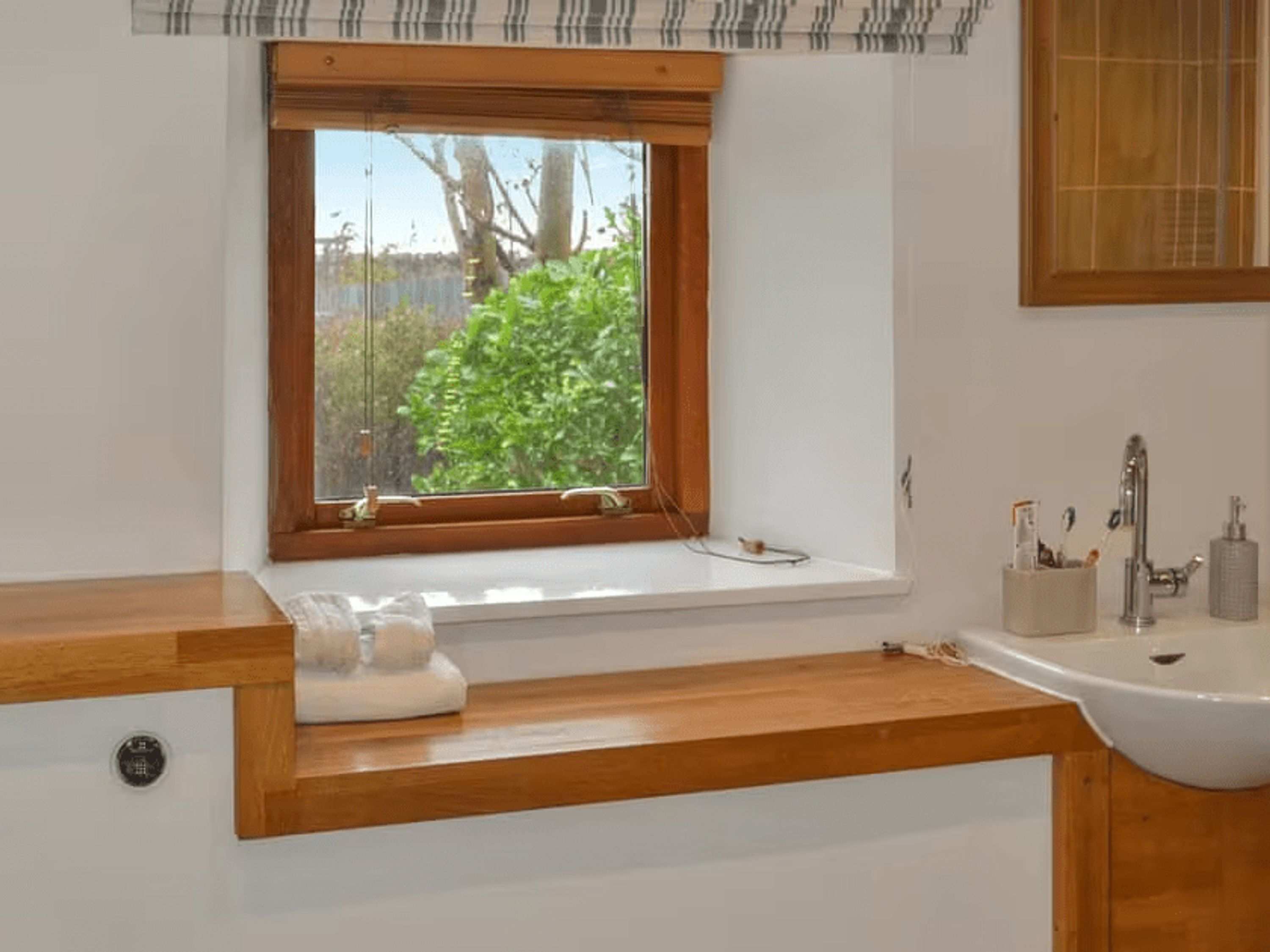 A bathroom with a window, a sink, and a mirror.
