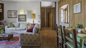 Un salon chaleureux avec des canapés à motifs, un plancher en bois et un coin repas comprenant des chaises et une table.