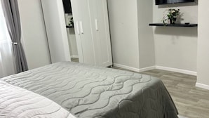A bedroom with a bed, a wardrobe, a TV mounted on the wall, and a small shelf with a plant. - Timco apartment with lake view (Torno)