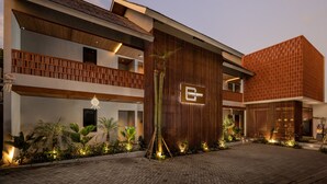 Un hôtel moderne à la façade en bois, doté d’une enseigne et d’une cour pavée agrémentée de plantes.