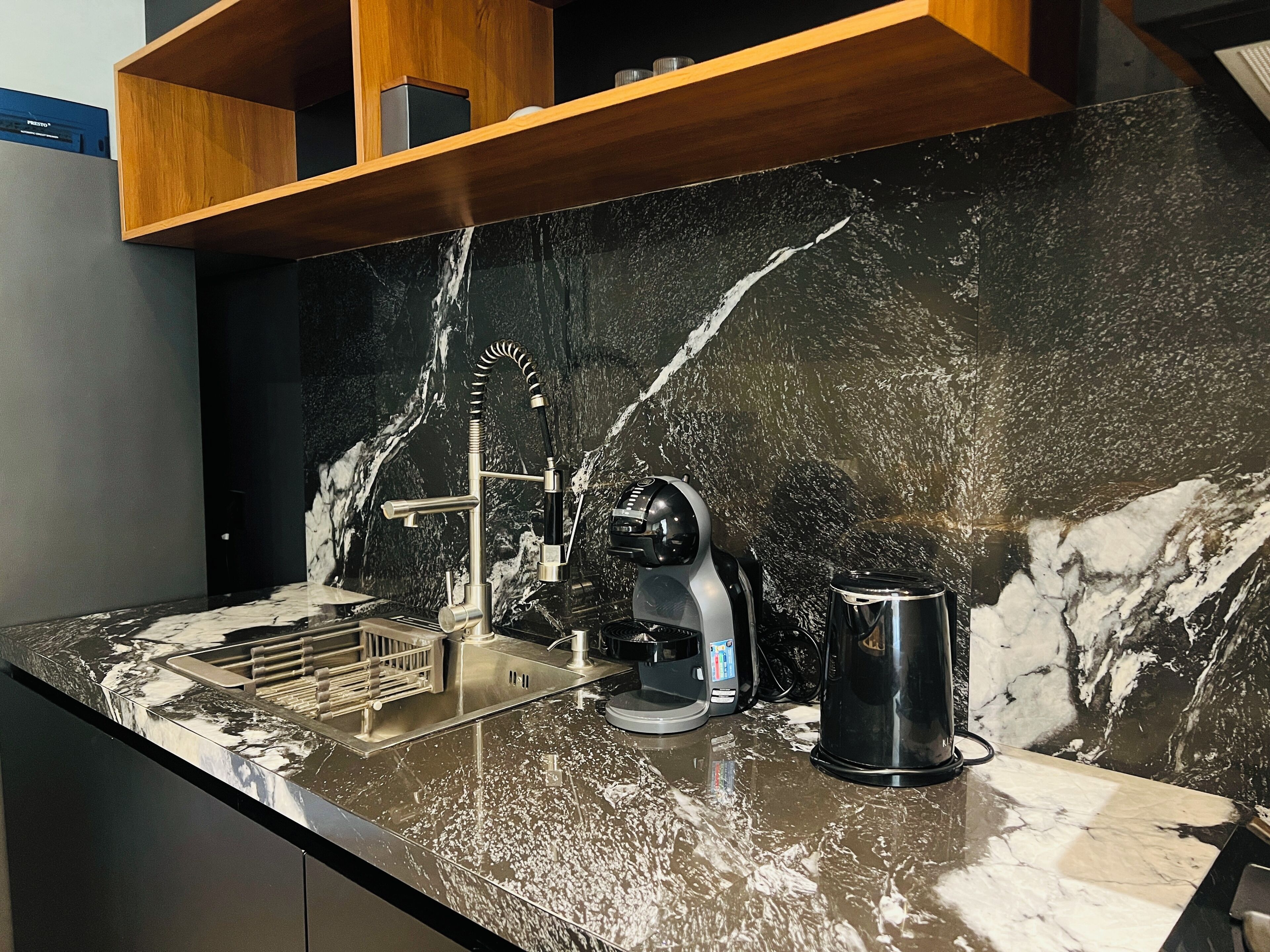 A kitchen with a marble backsplash, a coffee machine, and a kettle.