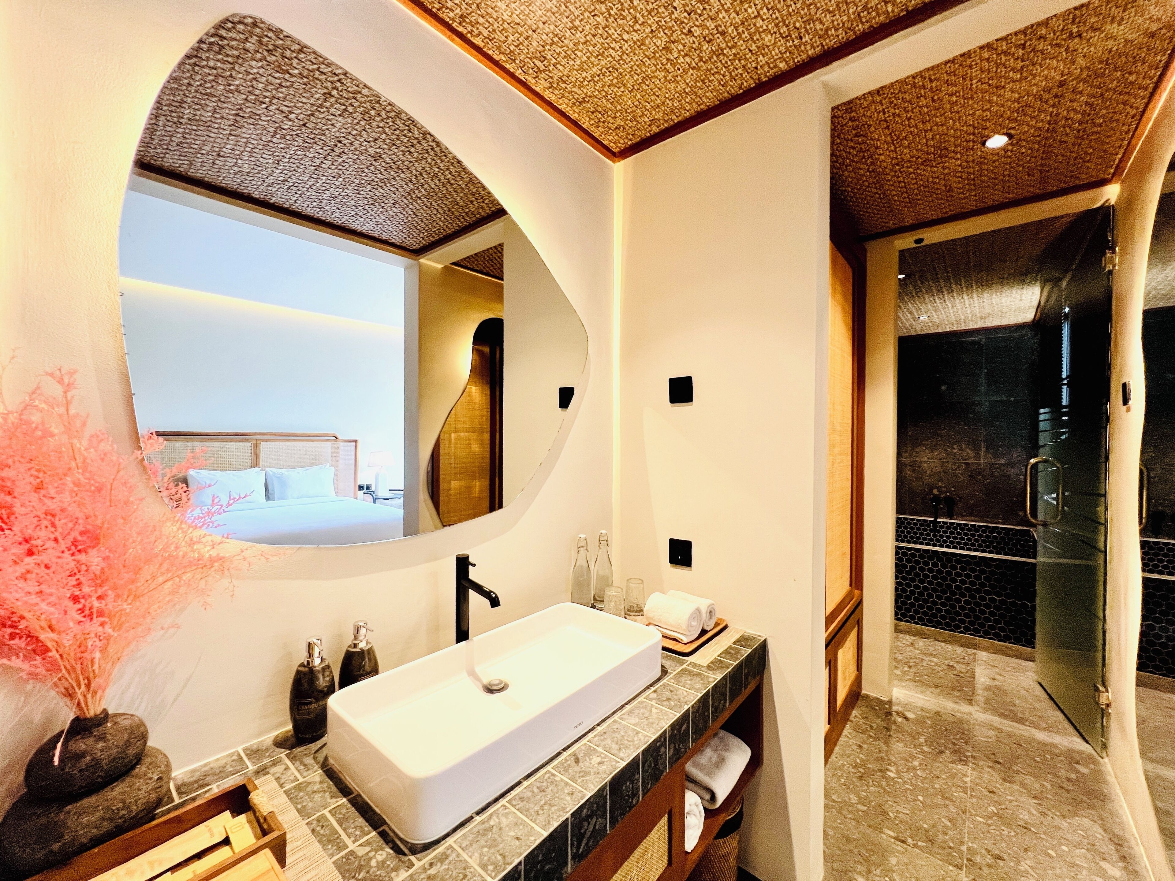 Un baño moderno con un espejo grande, un lavabo blanco y una zona de ducha.