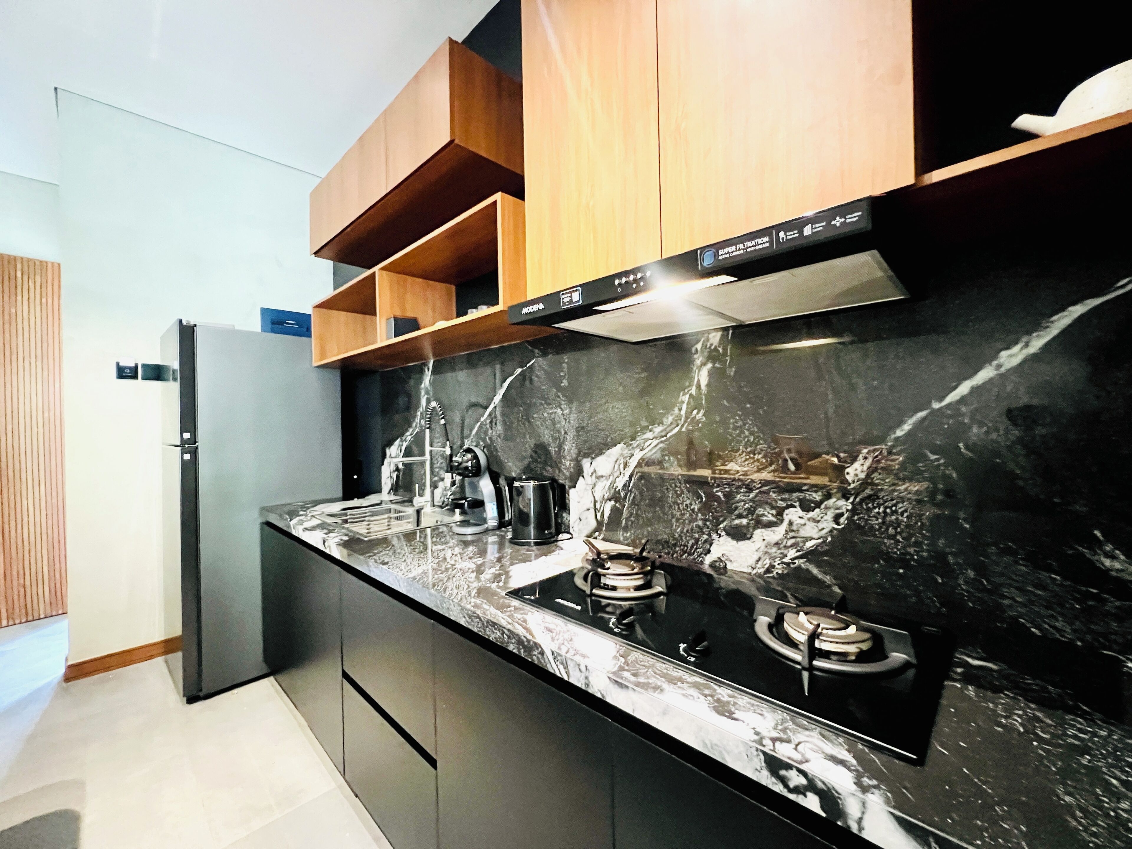 Una cocina moderna con encimera de mármol negro, electrodomésticos de acero inoxidable y armarios de madera.