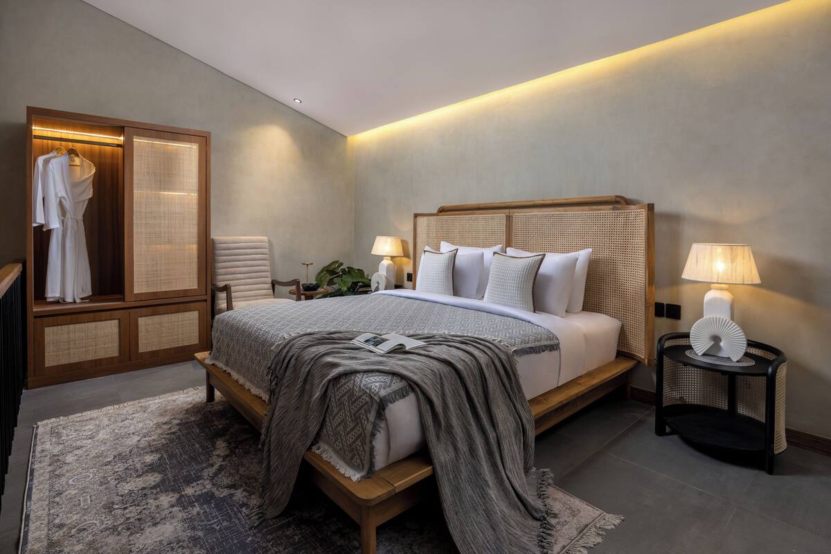 A modern bedroom with a large bed, bedside tables, a wardrobe, and a nightstand.