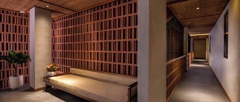 A corridor with a wooden bench, a potted plant, and a bamboo ceiling.