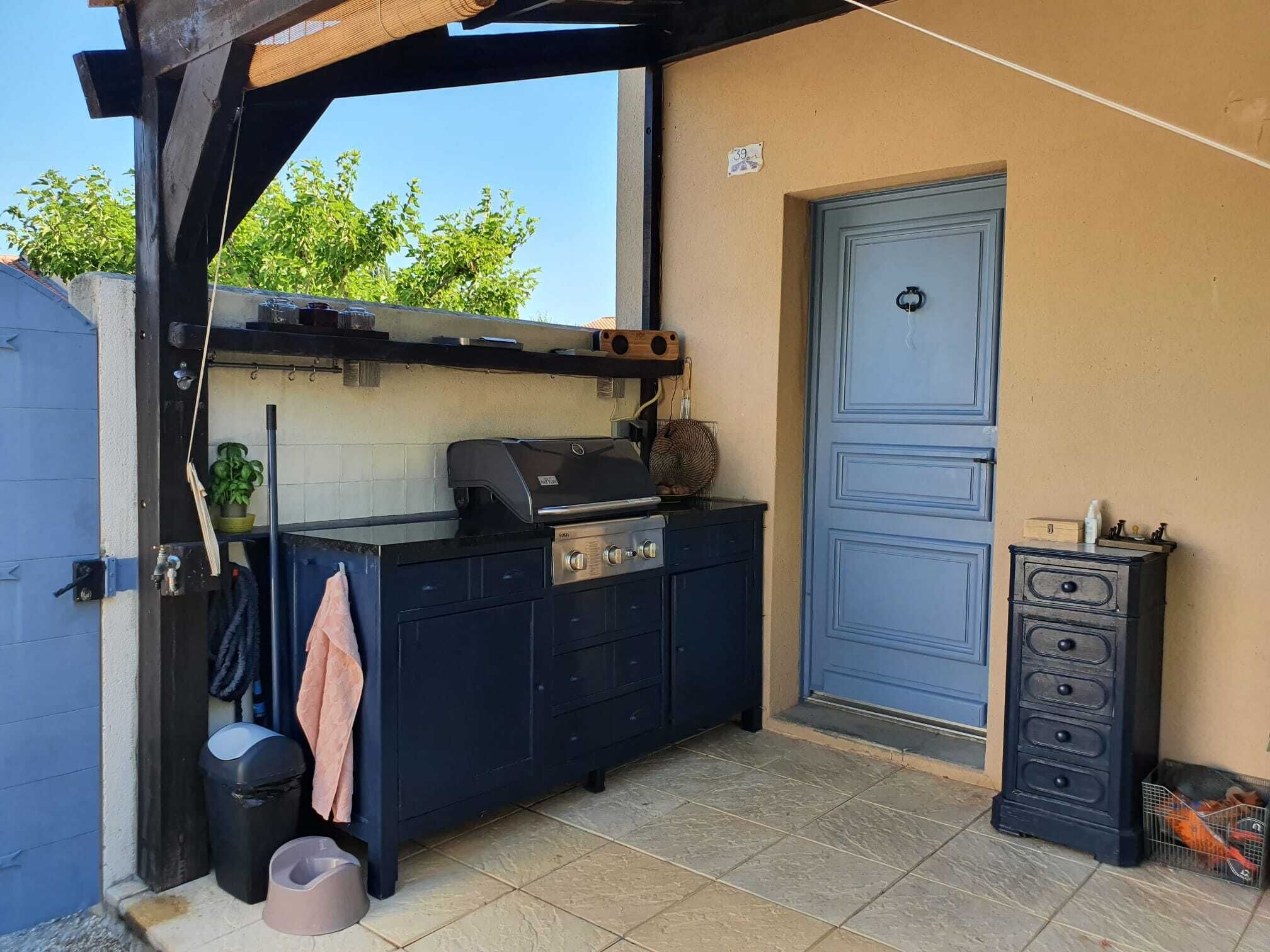 An outdoor kitchen area with a grill, a sink, and a small cabinet.