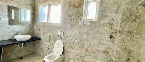 Une salle de bain avec un mur en marbre, un lavabo, des toilettes et une fenêtre.