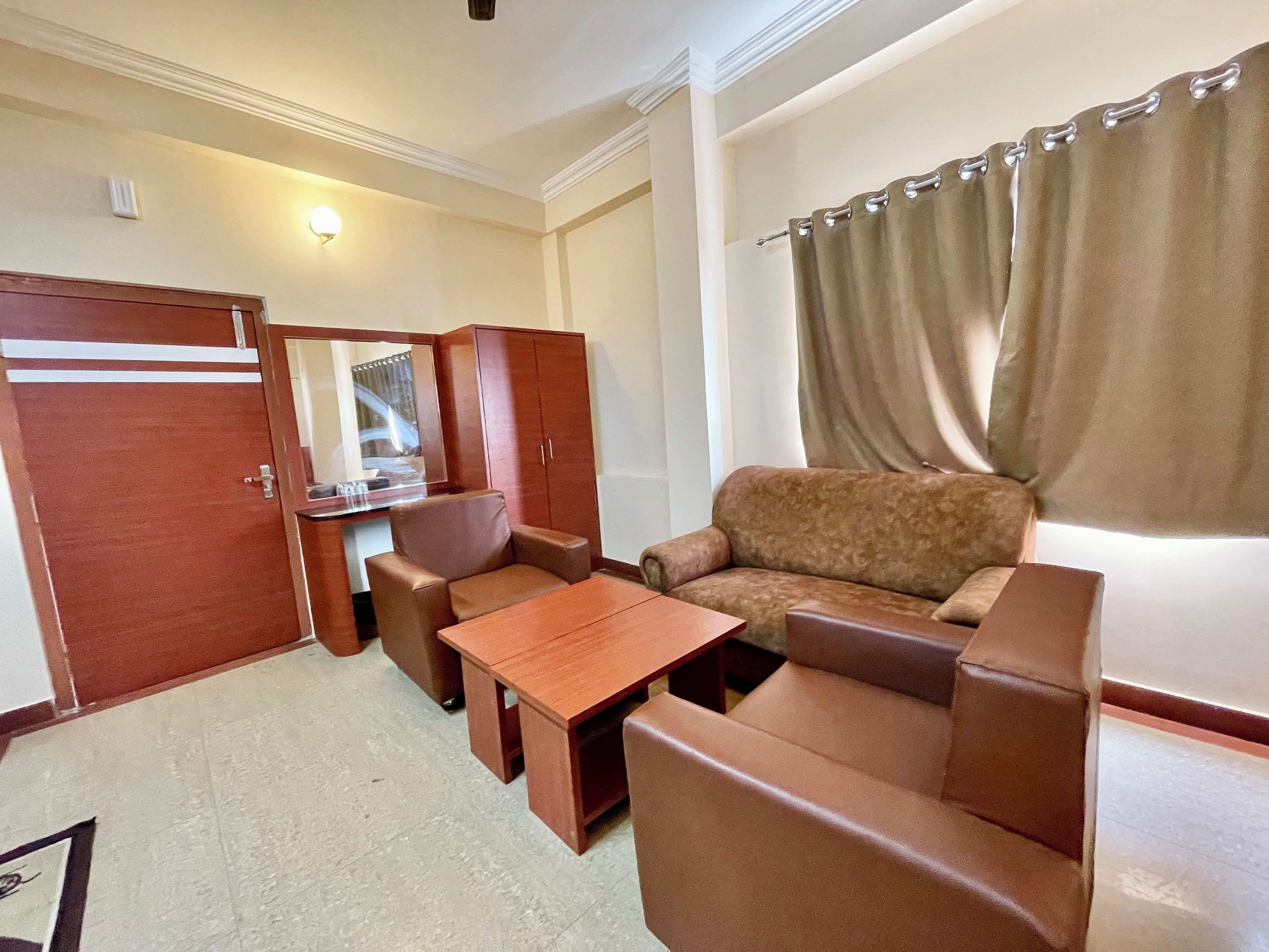 A compact living area with a sofa, two armchairs, a small table, and a wardrobe.