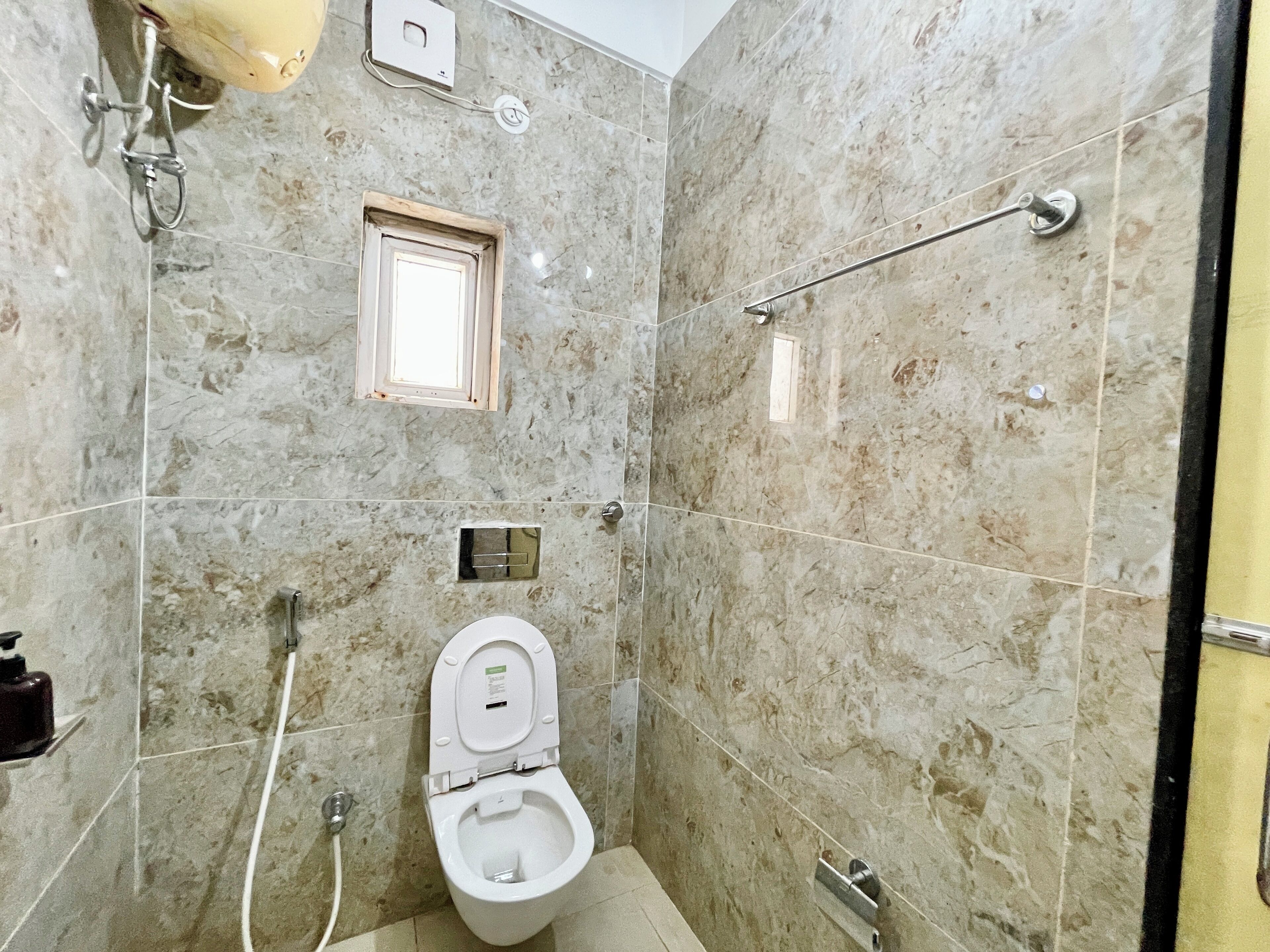 A bathroom with a toilet, a shower, and a handrail.