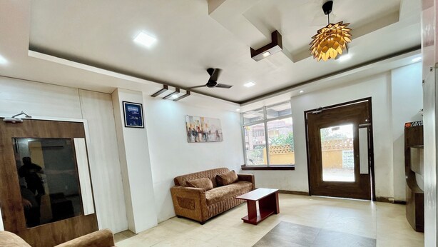 A modern hotel lobby with a brown sofa, a small table, and a ceiling fan. - Hotel Subham Beach Inn - near Sea Beach (Puri)