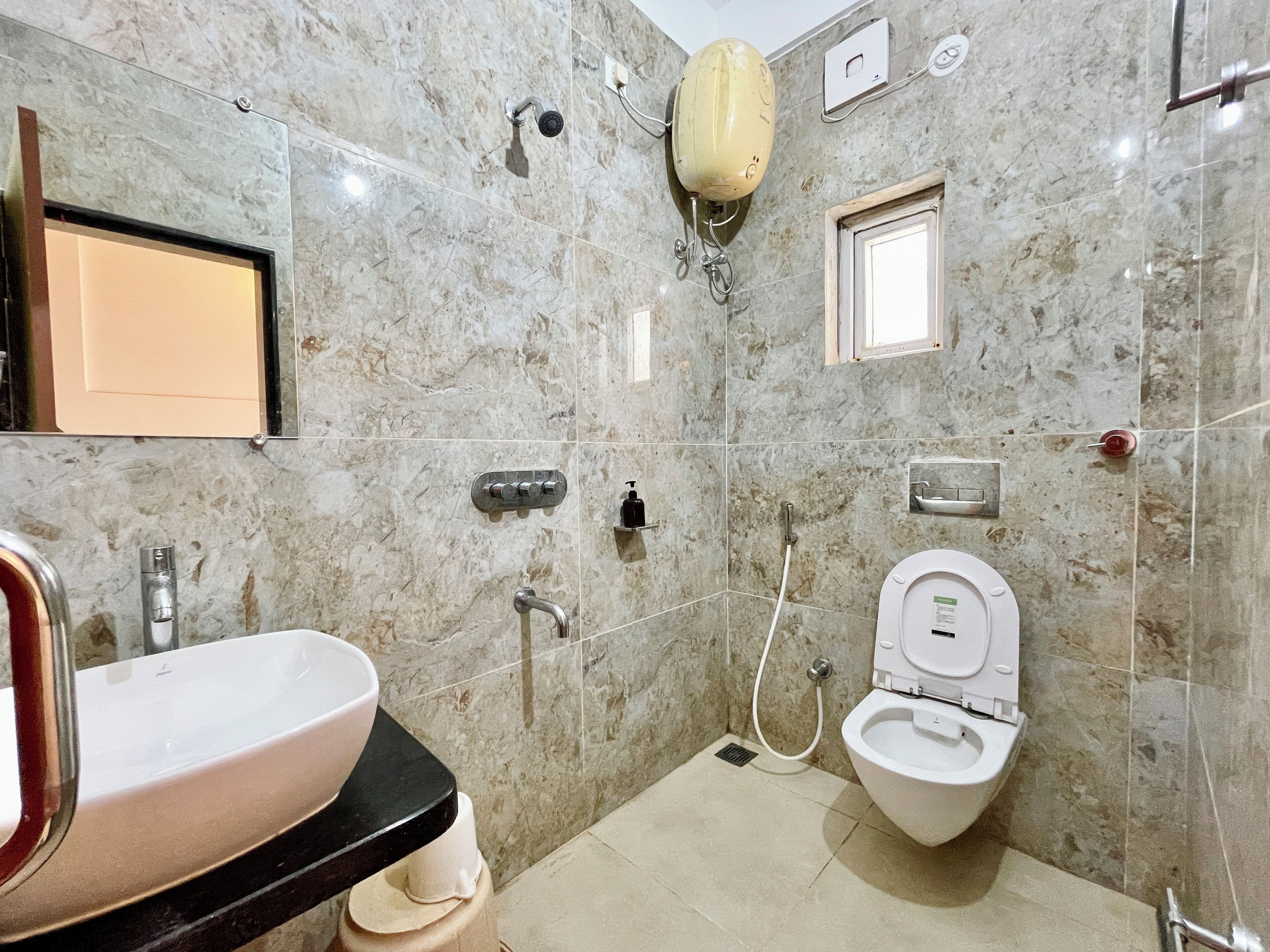 A bathroom with a marble floor, a sink, a toilet, and a shower with a handheld showerhead.